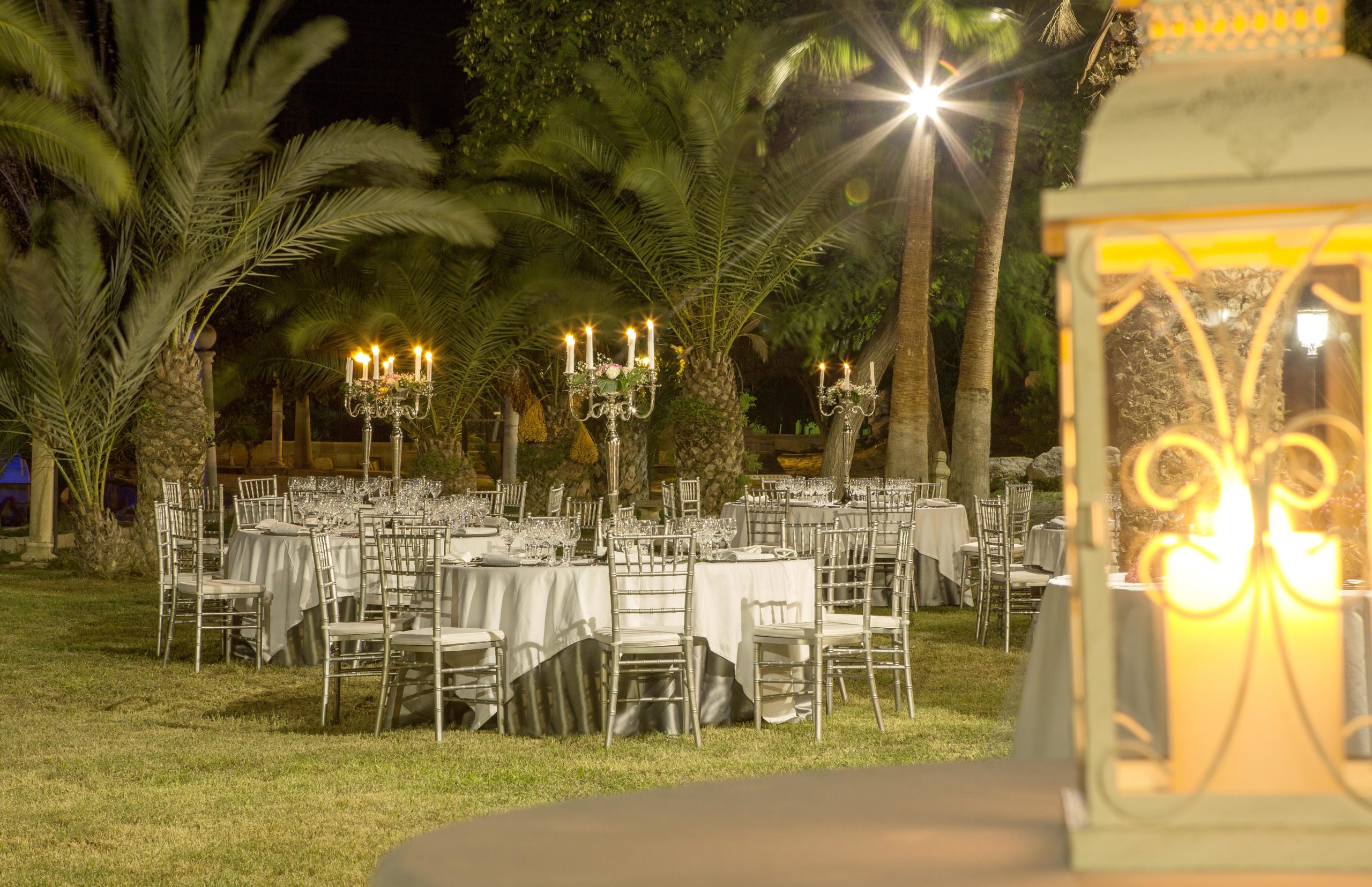 Vista tras foco de velas de salón exterior iluminado por candelabros.