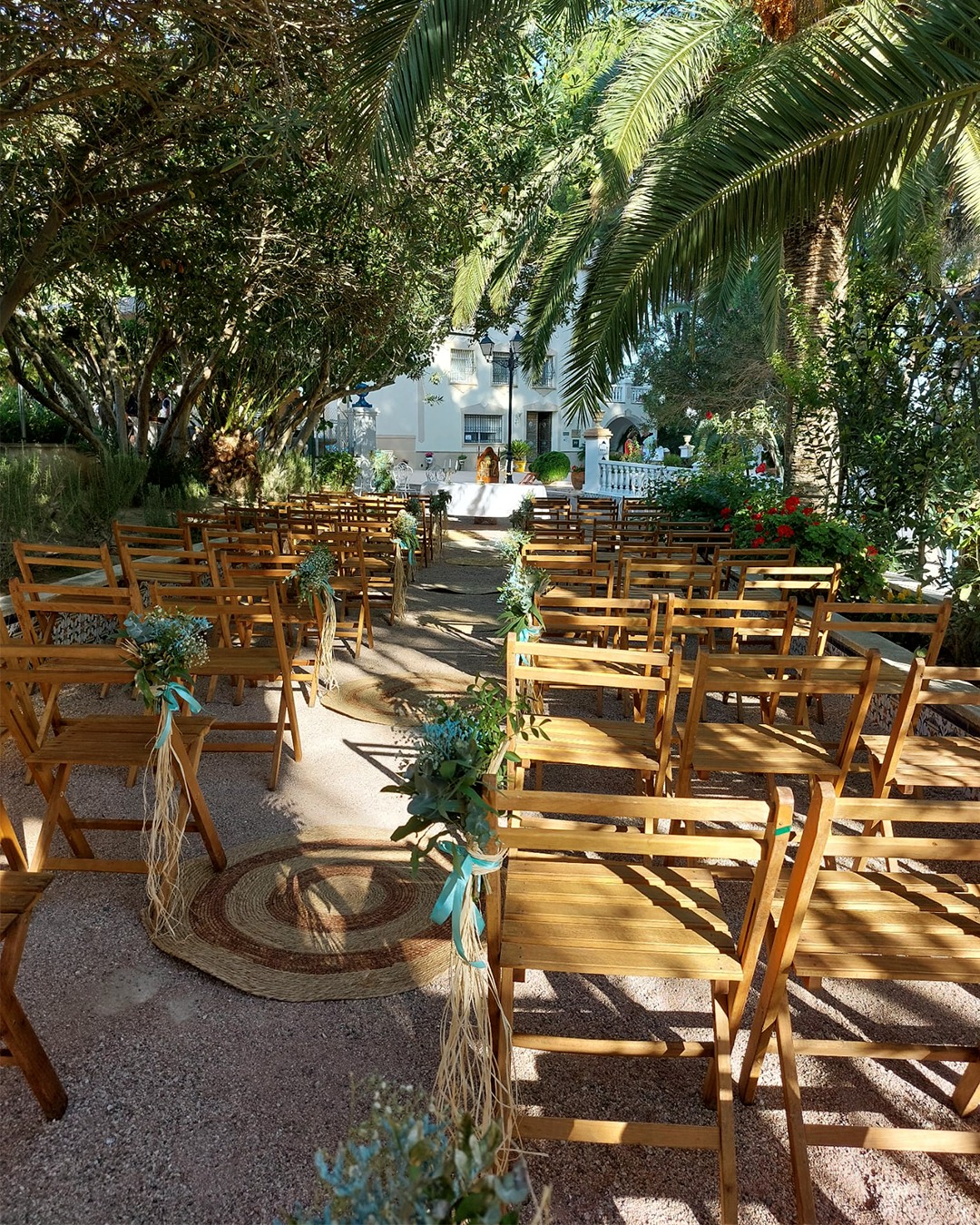 Boda exterior con altar rodeado por árboles, palmeras y flores.